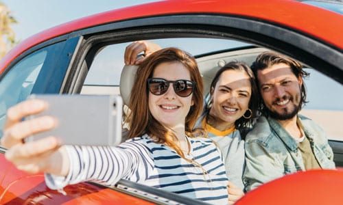 Young group of friends in car taking picture