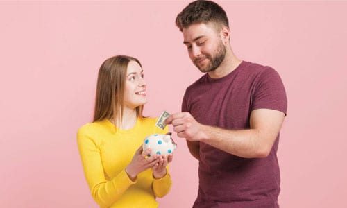 happy couple putting money in piggy bank